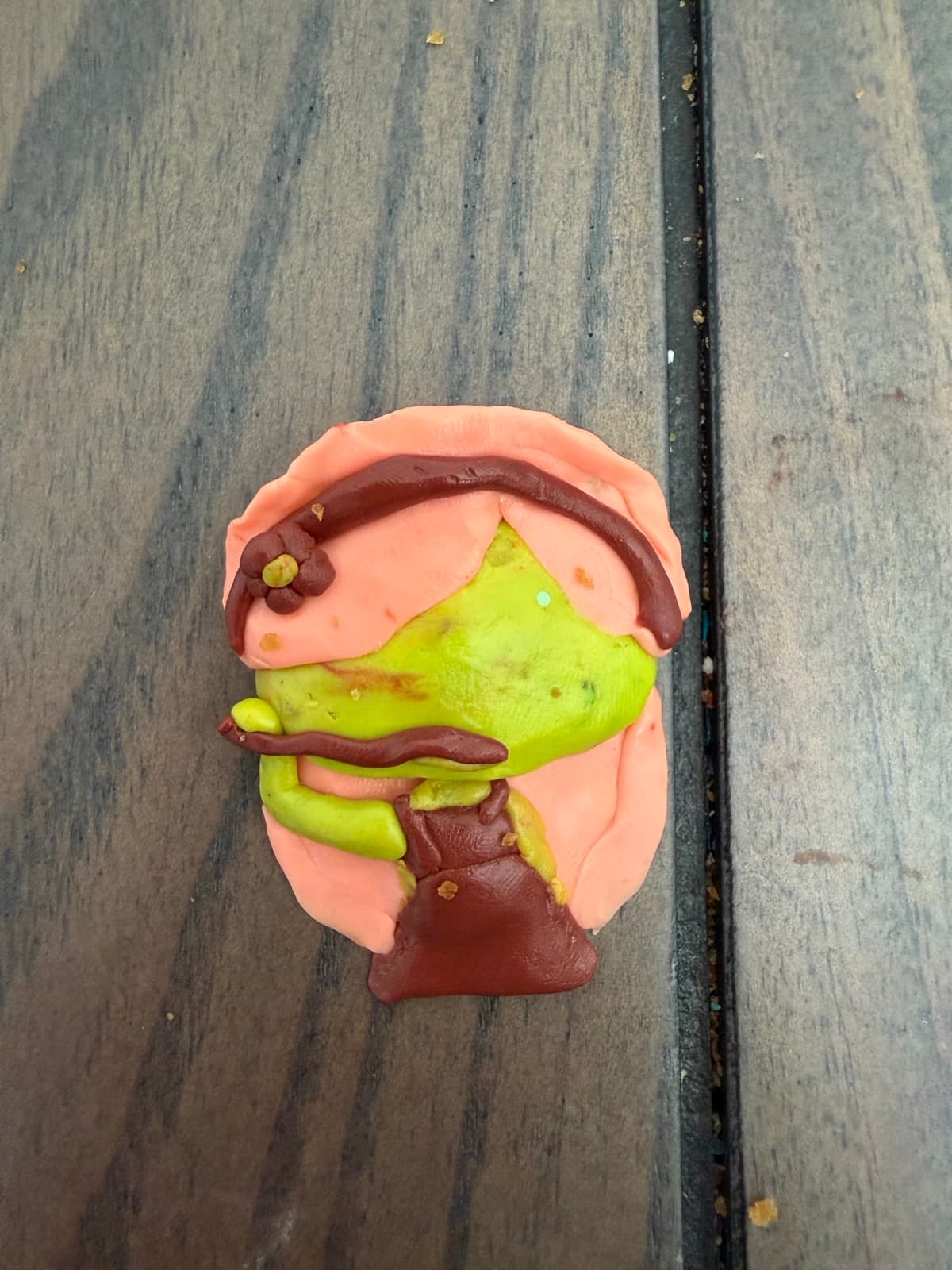 Small clay character in pink and green with a brown hat