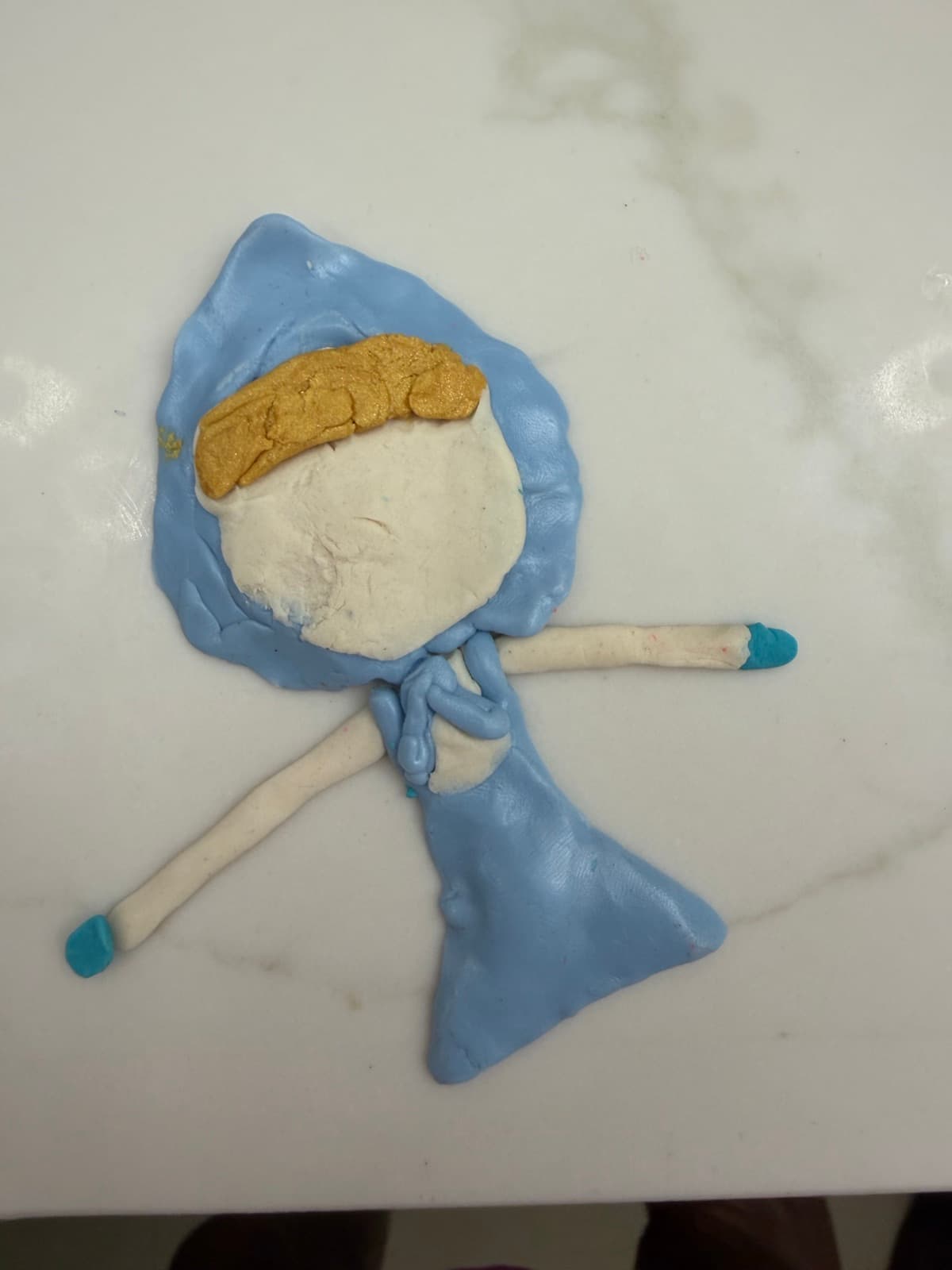 Clay figure of a girl in a blue dress and headscarf
