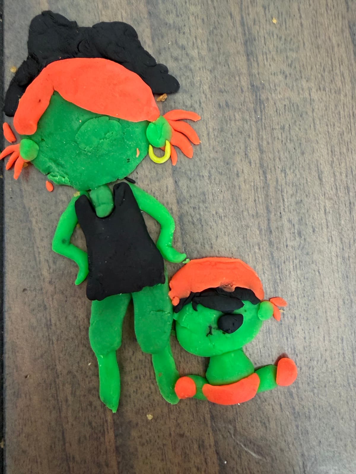 Clay figures of a girl and a baby in green and orange