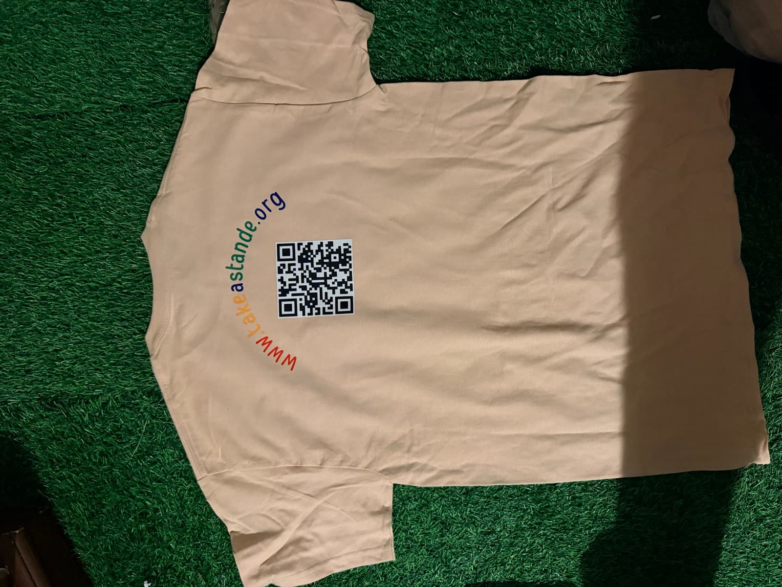 Photo of the printed tee, back, with QR code to takeastande.org